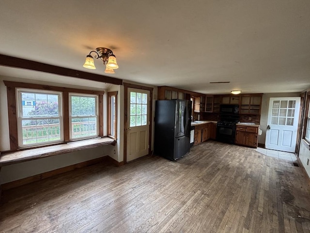 15 Reid Ave, Yarmouth, MA 02673 - kitchen with black appliances, wood finished floors, a sink, baseboards, and brown cabinets