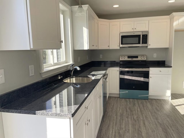 kitchen with stainless steel appliances, white cabinetry, hanging light fixtures, and dark hardwood / wood-style floors