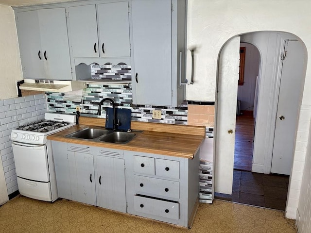 kitchen featuring sink, backsplash, butcher block countertops, and gas range gas stove