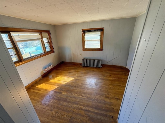 unfurnished room featuring radiator, a wealth of natural light, ornamental molding, and dark hardwood / wood-style floors