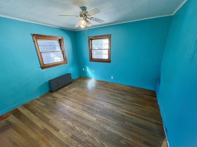 empty room with dark wood-type flooring, ornamental molding, radiator heating unit, and ceiling fan