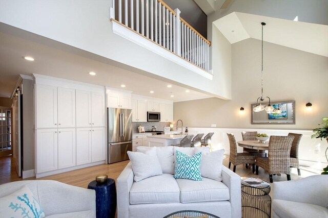 living room featuring light wood finished floors, a high ceiling, recessed lighting, and a notable chandelier