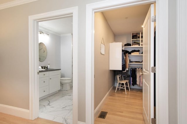 hallway with visible vents, baseboards, a sink, and marble finish floor