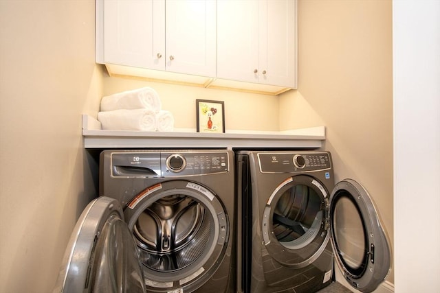 clothes washing area with cabinet space and independent washer and dryer