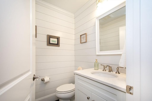 half bath with toilet, ornamental molding, and vanity