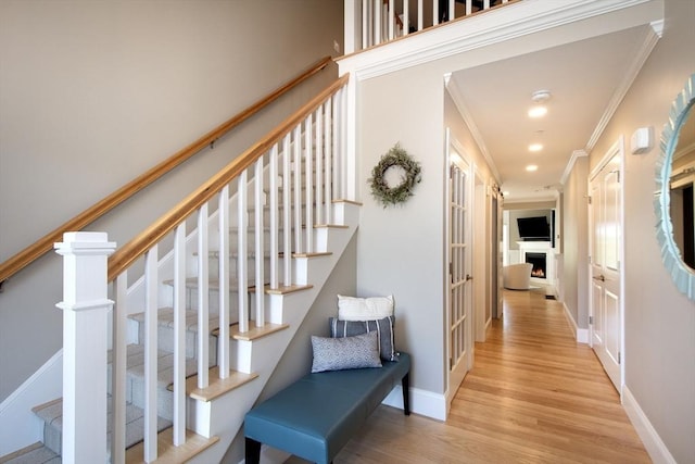 stairs with recessed lighting, wood finished floors, baseboards, and ornamental molding