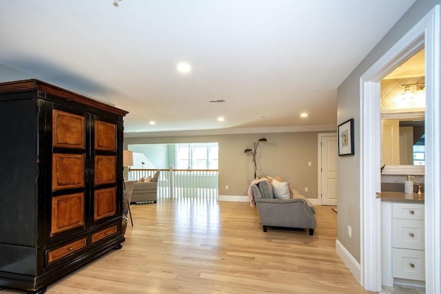 living area featuring recessed lighting, light wood finished floors, ornamental molding, an upstairs landing, and baseboards