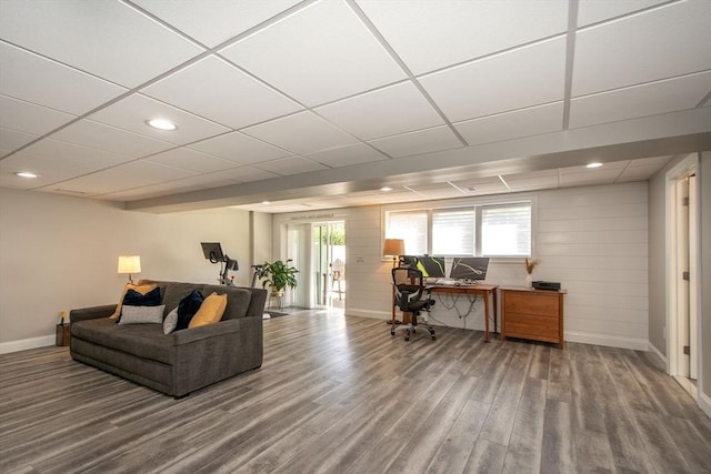 living room with wood finished floors, a drop ceiling, and baseboards