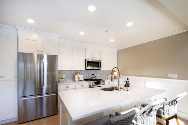 kitchen featuring white cabinets, appliances with stainless steel finishes, a breakfast bar area, and a sink