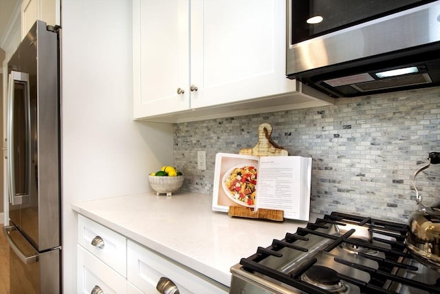 kitchen with white cabinets, light countertops, appliances with stainless steel finishes, and tasteful backsplash