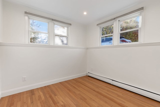 spare room featuring hardwood / wood-style flooring, plenty of natural light, and a baseboard heating unit