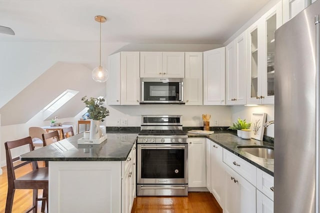 kitchen featuring pendant lighting, a breakfast bar, a skylight, appliances with stainless steel finishes, and white cabinetry