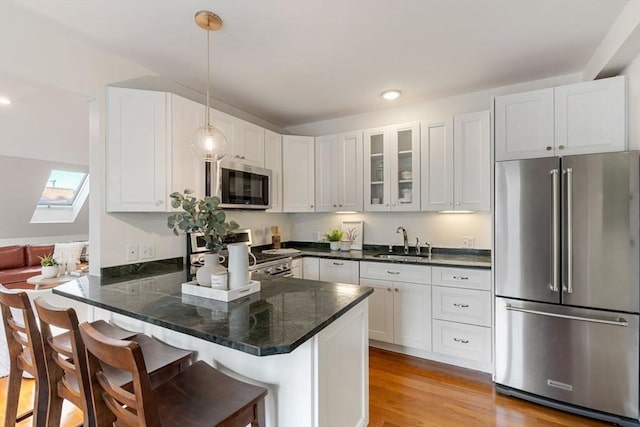 kitchen featuring a kitchen breakfast bar, kitchen peninsula, stainless steel appliances, and hanging light fixtures