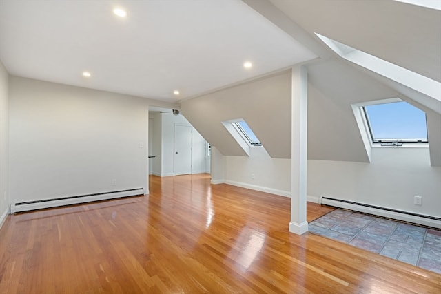 bonus room featuring light hardwood / wood-style floors, a baseboard heating unit, and vaulted ceiling with skylight