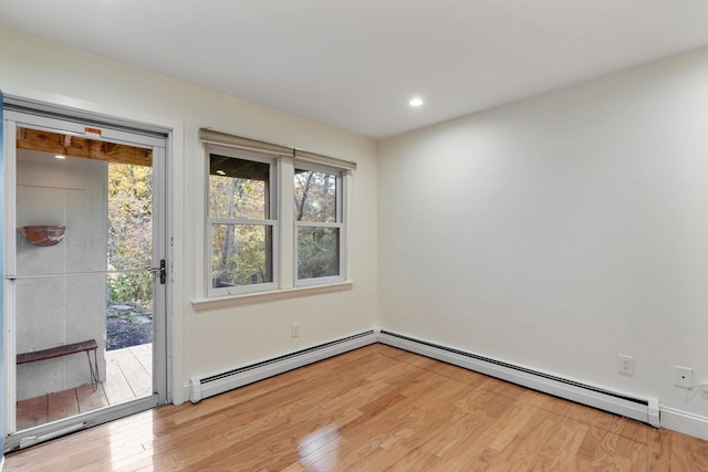 unfurnished room featuring baseboard heating and light hardwood / wood-style floors