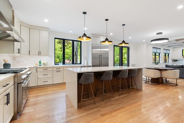 92 Cedar St, Lexington, MA 02421 - kitchen featuring wall chimney range hood, high end appliances, light wood-type flooring, open floor plan, and a center island