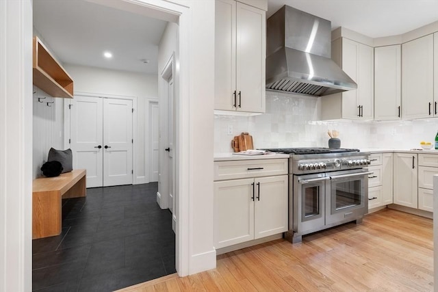 92 Cedar St, Lexington, MA 02421 - kitchen with wall chimney exhaust hood, range with two ovens, decorative backsplash, light countertops, and white cabinetry