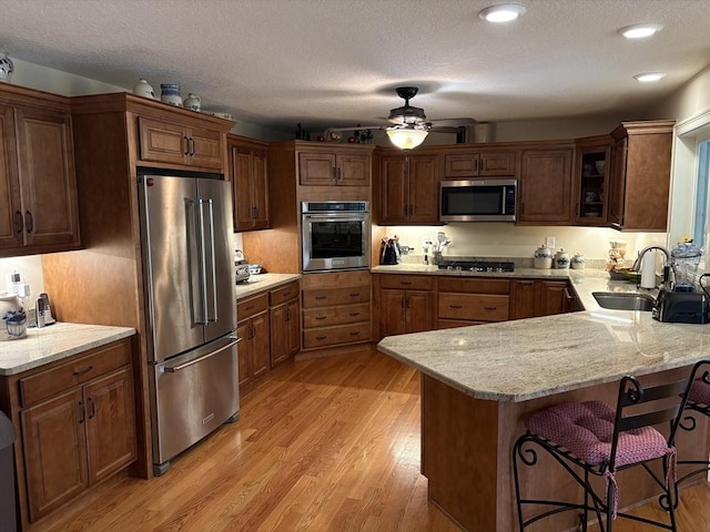 43 Caddyshack Dr, Chicopee, MA 01020 - kitchen with appliances with stainless steel finishes, a peninsula, ceiling fan, a kitchen breakfast bar, and light wood-style floors