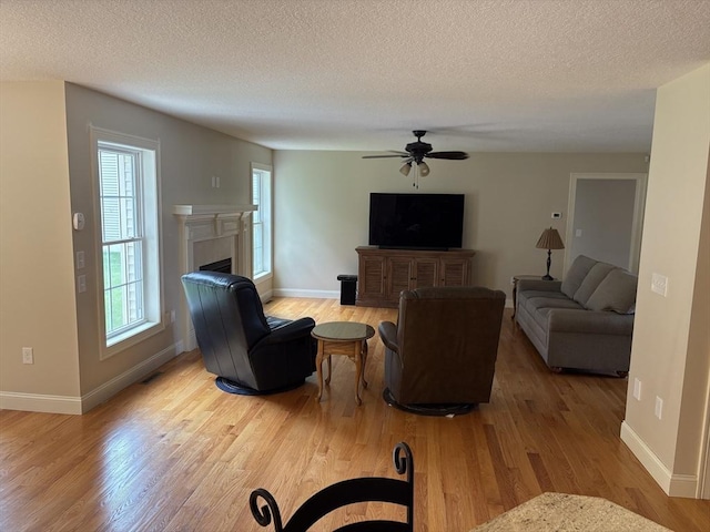 43 Caddyshack Dr, Chicopee, MA 01020 - living room with wood finished floors, a ceiling fan, a fireplace, and a textured ceiling