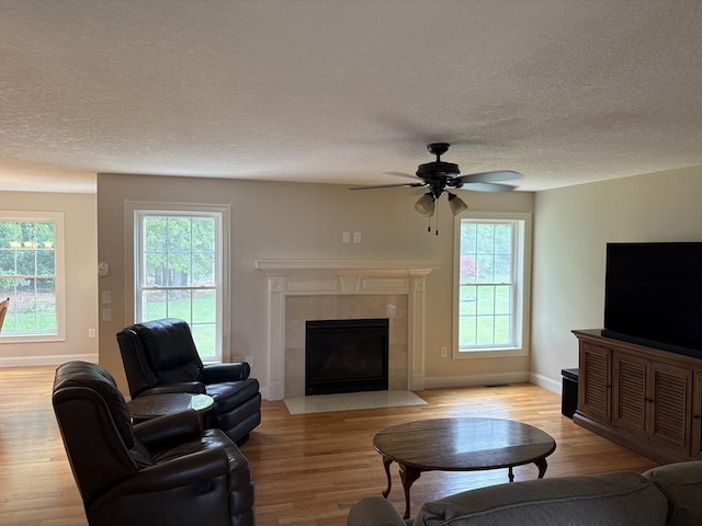 43 Caddyshack Dr, Chicopee, MA 01020 - living room with light wood finished floors, a textured ceiling, a ceiling fan, and a fireplace