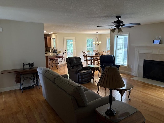 43 Caddyshack Dr, Chicopee, MA 01020 - living area featuring light wood finished floors, a textured ceiling, ceiling fan, a chandelier, and a high end fireplace