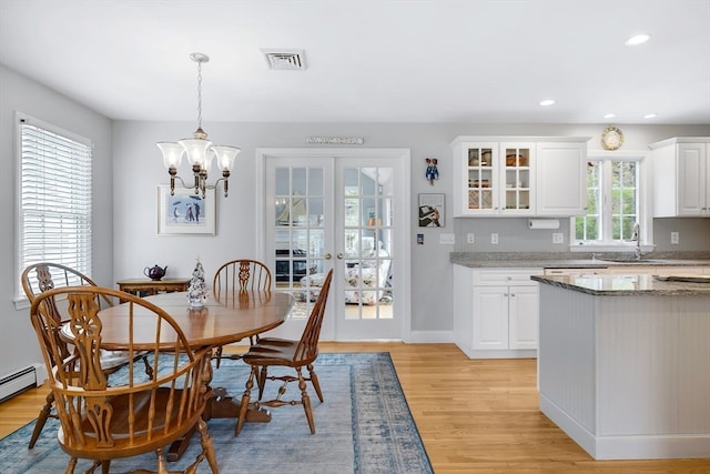 dining area featuring light hardwood / wood-style flooring, a notable chandelier, a baseboard heating unit, sink, and french doors