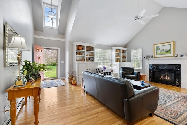 living room with a wealth of natural light, high vaulted ceiling, light wood-type flooring, and a high end fireplace