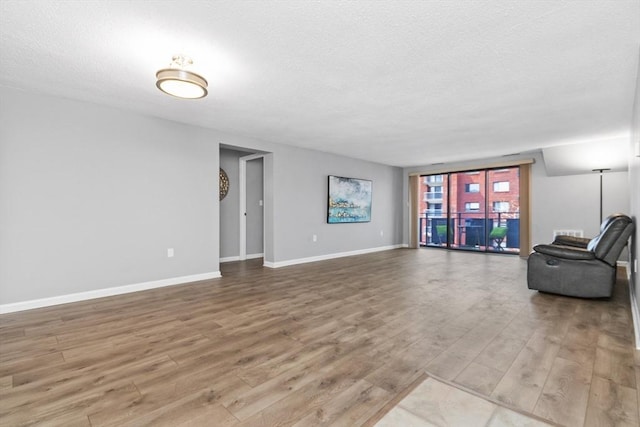 living room featuring baseboards, a textured ceiling, and wood finished floors