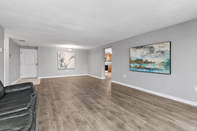 unfurnished living room with baseboards, a textured ceiling, and wood finished floors