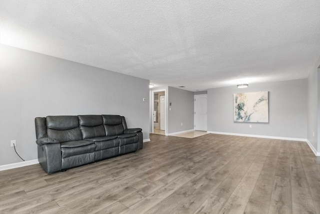 living area featuring baseboards, a textured ceiling, and wood finished floors