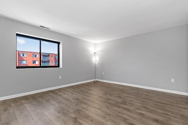 empty room with baseboards, wood finished floors, and visible vents