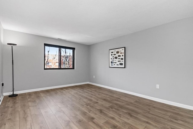 spare room featuring baseboards and wood finished floors