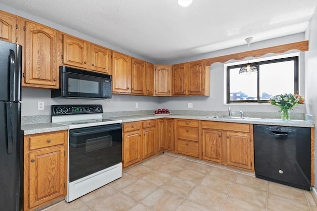 kitchen featuring brown cabinetry, light countertops, a sink, black appliances, and decorative light fixtures