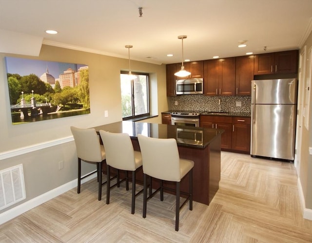 kitchen with a kitchen breakfast bar, visible vents, dark countertops, a sink, and stainless steel appliances