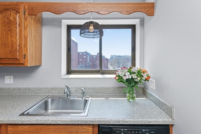 kitchen with black dishwasher, light countertops, brown cabinets, a sink, and hanging light fixtures