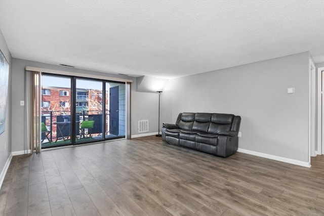 sitting room featuring a textured ceiling, baseboards, visible vents, and wood finished floors