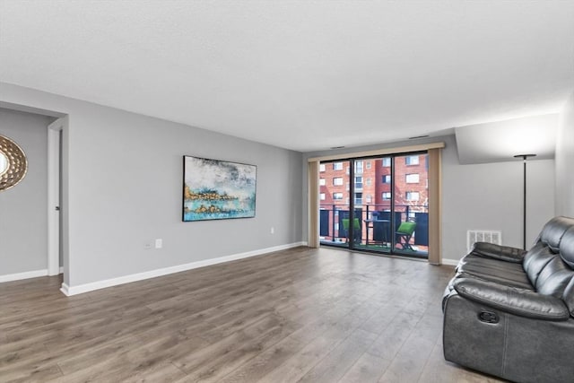 living room featuring baseboards, wood finished floors, and visible vents