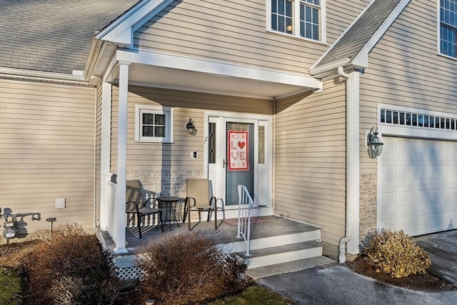 view of exterior entry with a garage and covered porch