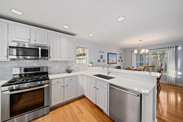 kitchen with white cabinetry, stainless steel appliances, kitchen peninsula, and sink