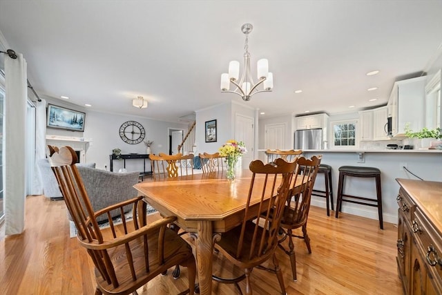 dining area with an inviting chandelier, crown molding, and light wood-type flooring