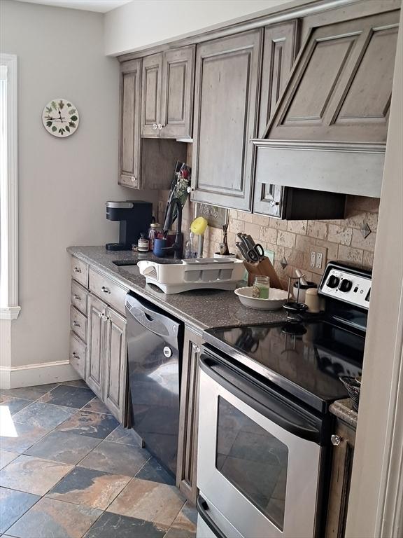 3901 Woodbridge Rd Unit 3901, Peabody, MA 01960 - kitchen with stainless steel range with electric cooktop, dishwasher, backsplash, stone tile flooring, and baseboards