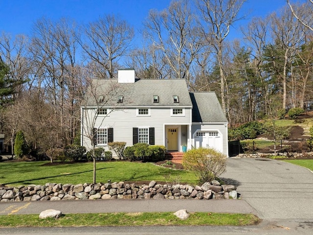 view of front of home featuring a garage, a front yard, fence, a chimney, and driveway