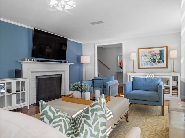 living area with stairway, wood finished floors, and a fireplace
