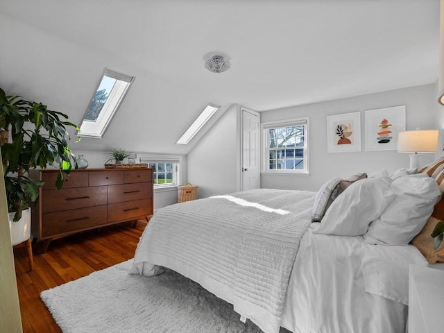 bedroom featuring multiple windows, lofted ceiling with skylight, and wood finished floors