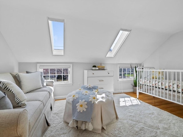 bedroom with vaulted ceiling with skylight, wood finished floors, and baseboards