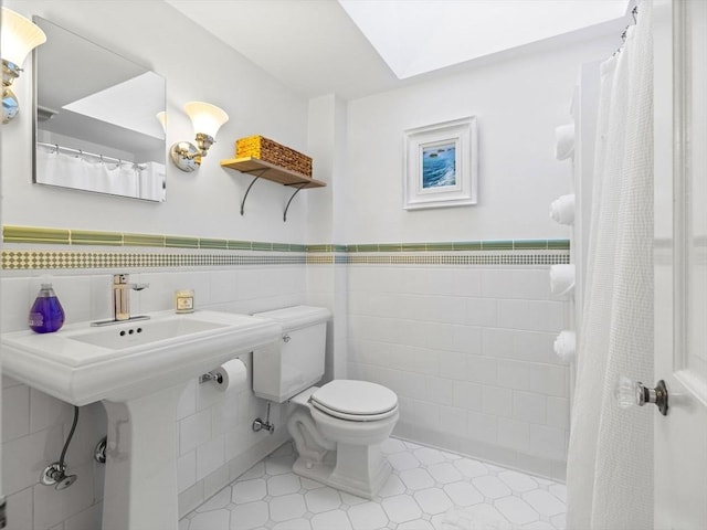 full bathroom featuring toilet, a shower with curtain, a wainscoted wall, and tile walls