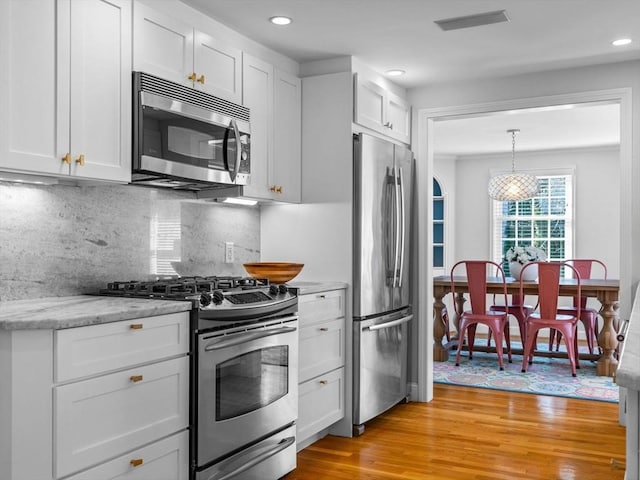 kitchen with tasteful backsplash, recessed lighting, white cabinets, appliances with stainless steel finishes, and light wood finished floors