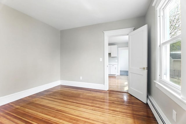 empty room featuring baseboards, wood finished floors, and a baseboard radiator