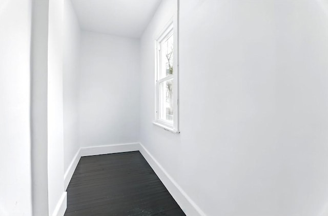 hallway featuring dark wood-style flooring and baseboards