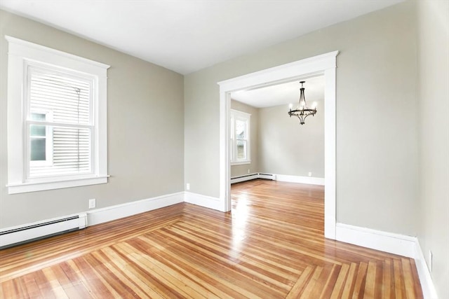 unfurnished room featuring a baseboard heating unit, an inviting chandelier, light wood-style flooring, baseboard heating, and baseboards
